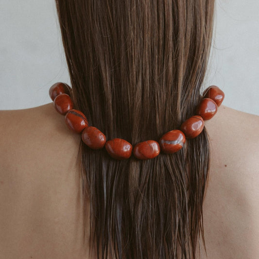 Model wearing minimalist Red Jasper necklace for grounding and strength, styled with neutral-toned outfit – crystal jewelry by Stellar Whispers.