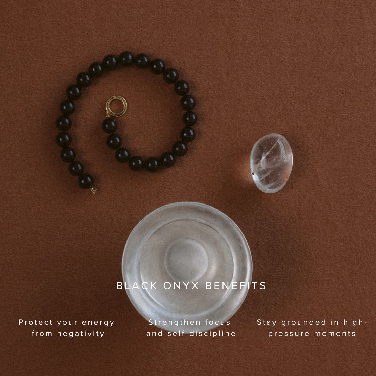 Flat lay of the Grace Black Onyx Necklace arranged in a loose curve on a warm brown background, paired with a clear quartz crystal and a small white ceramic bowl. Text highlights the benefits of black onyx: protecting energy, enhancing focus, and staying grounded.