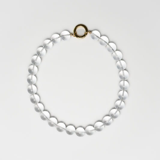 Clear Quartz bead necklace with a round gold clasp, laid flat in a circular shape on a white background.
